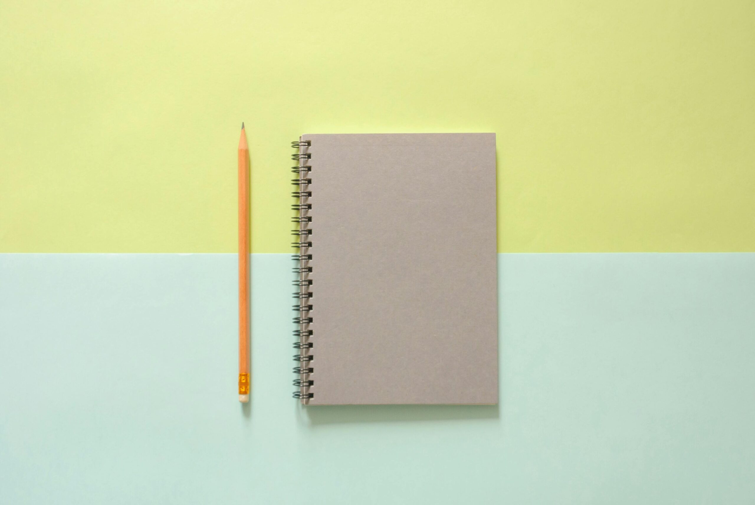 White Spiral Notebook Beside Orange Pencil